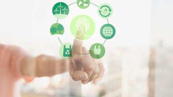 Pessoa interagindo com ícones de sustentabilidade ambiental, energia renovável e reciclagem em tela digital, representando práticas ASG nos investimentos.