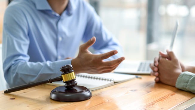Duas pessoas discutindo questões jurídicas em mesa com martelo de juiz, representando decisões judiciais e impactos legais na gestão pública e previdência dos servidores.