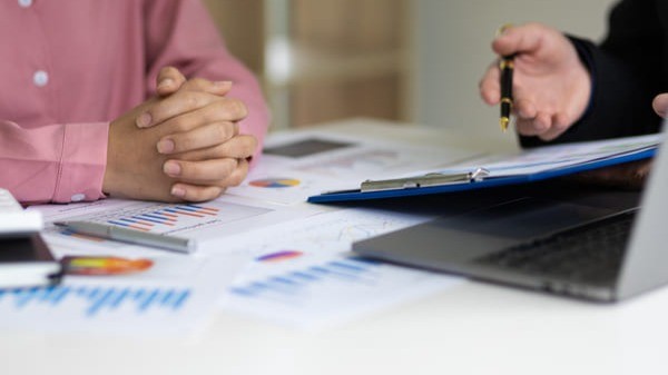 Pessoas analisando gráficos e documentos financeiros em reunião, representando o planejamento da Política de Investimentos e a gestão estratégica dos recursos dos RPPS.